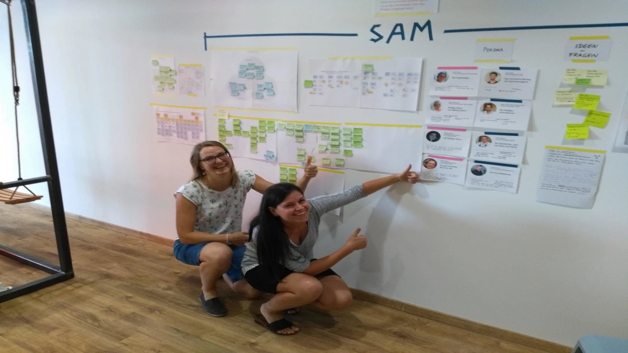 Two team members presenting UX and workflow diagrams on a whiteboard wall during a design workshop at Peerox.